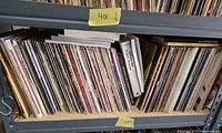 Two shelf rows filled with tightly packed vinyl records, yellow notes showing lot number