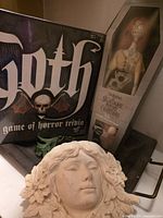 Front view of Goth board game, Sally doll boxed, decorative head plaque