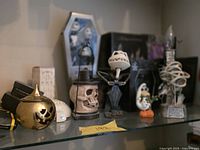 Lower shelf showing NBC figures, gold pumpkin lantern, skull lantern, coffin-box Jack figure, Spiral Hill diorama, Zero figure, tombstone