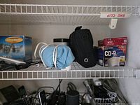 Top shelf with box of blank CD-Rs, blue pouch, camera case and other items