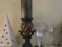 Close-up of left candlestick with patterned candle, stone lantern, and two glass stem holders