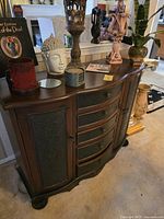 Front view of dark brown solid wood console cabinet with embossed metal panels, five drawers, two side doors