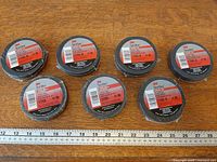 Seven rolls of 3M Temflex Cotton Friction Tape with ruler for scale on wooden surface