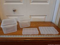 Four plastic containers laid out with ruler for scale