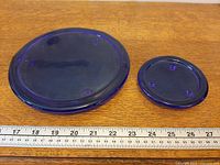 Large and small cobalt blue glass plates beside ruler showing size