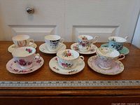 All seven teacup and saucer sets arranged with ruler for scale