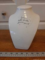 Front view of white ceramic necklace display stand with printed quote