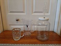 All three items side by side on table: mug, pitcher, fermentation jar with airlock