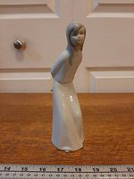 Front view of porcelain girl figurine with ruler for scale