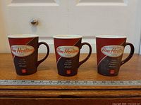 Front view of three Tim Hortons ceramic mugs showing logo and exterior design