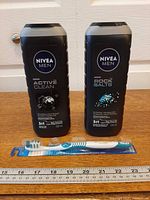 Two Nivea Men shower gels and sealed toothbrush displayed with ruler