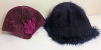 Burgundy felt cloche hat with bow next to navy fuzzy cloche hat