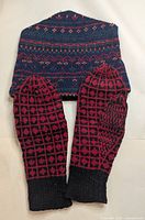 Hat and pair of mittens laid flat showing patterns and colours