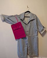 Full view of striped coat on hanger with pink tote bag