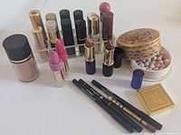 Group shot of entire cosmetics lot including foundation, organizer with lipsticks, pearls tin, compact, liners