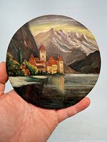 Front view of round landscape painting held in hand
