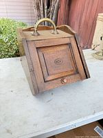 Front view of oak coal scuttle showing door, inlay, knob, brass handle