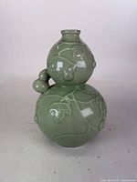 Front view of jade-green double-gourd celadon vase showing raised vine decoration