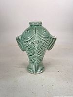 Front view of jade-green twin fish celadon vase showing scale detail and fluted foot