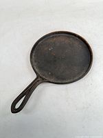 Full view of round cast iron griddle showing cooking surface and handle