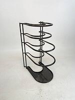 front view of vertical black metal skillet rack showing five curved tiers and base