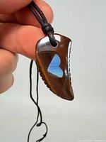 Full view of tooth-shaped pendant on black cord showing overall design