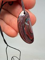 Front view of polished opal-rich stone pendant on cord
