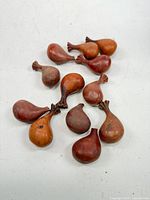 Group of twelve small hand-carved wooden gourd-shaped pieces displayed on white surface