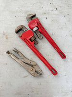 overview of two red pipe wrenches and silver locking pliers