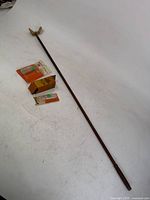 Full view of wooden cleaning handle with attached cotton head and three packaged cleaning pads