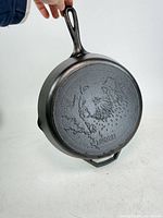 Full view of cast-iron skillet underside showing bear design and handle.