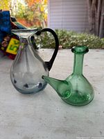 Clear pitcher with black handle and green side-spout vessel on table