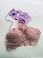 Pink lace bra and lavender bikini top laid out