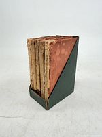 Five miniature books in green slipcase showing worn spines
