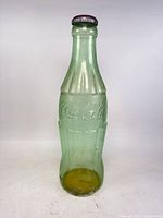 Front view of oversized green Coca-Cola bottle piggy bank
