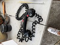 Full view of black handset with coiled cords and red button