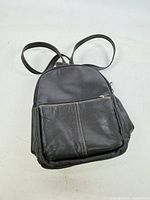 Front view of black leather purse backpack showing front zip pocket and overall style