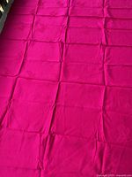 Full view of fuchsia silk yardage laid flat showing size and folds