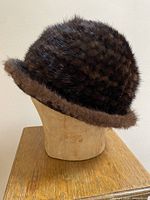 Front three-quarter view of dark brown mink hat on stand