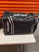 Top and side view of black Bauer hockey duffel bag on table