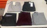Five folded trousers on table showing colours and tags
