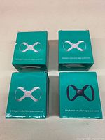 Four teal boxes of intelligent induction posture correctors, two with white device image, two with black device image