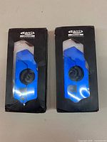 Front view of two boxed Garris handlebar locks showing blue anodized devices through packaging window