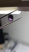 Pear-shape purple spinel held by tweezers side profile