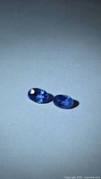 Pair of oval blue sapphires on neutral background