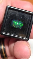 Front view of rectangular black opal showing green and blue play-of-color