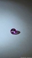 Faceted hot pink gemstone on neutral background