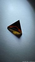 Triangular deep orange tourmaline resting on surface