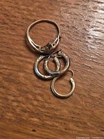 Gold ring and three hoop earrings on wood surface