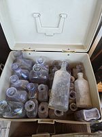 Open plastic container filled with old clear glass bottles